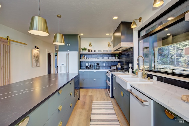 kitchen featuring a sink, wall chimney range hood, a barn door, white appliances, and open shelves