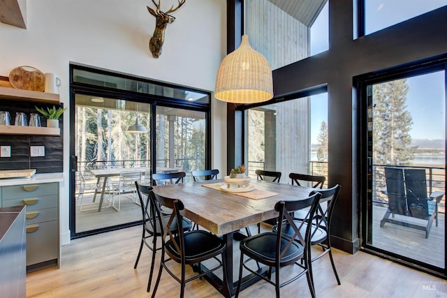 dining space with a wealth of natural light, light wood-style floors, and a high ceiling