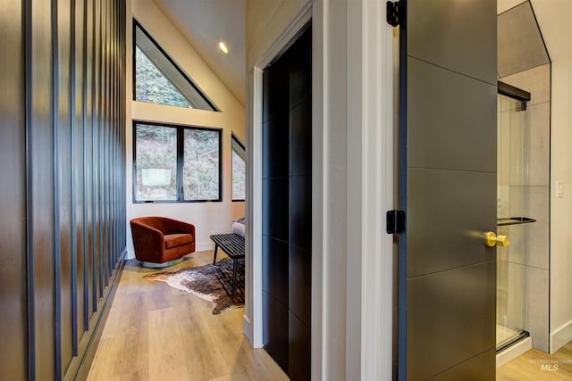 hall featuring light wood finished floors and lofted ceiling