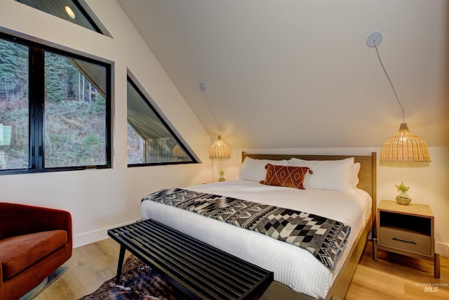 bedroom with vaulted ceiling, light wood-style flooring, and baseboards