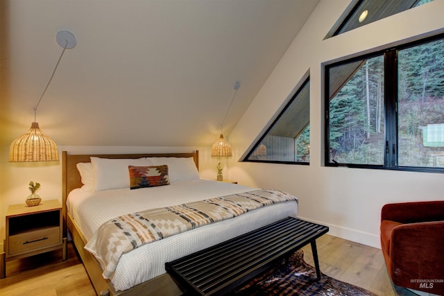 bedroom with light wood-style flooring, baseboards, and lofted ceiling