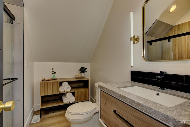 full bathroom with visible vents, toilet, vaulted ceiling, wood finished floors, and vanity