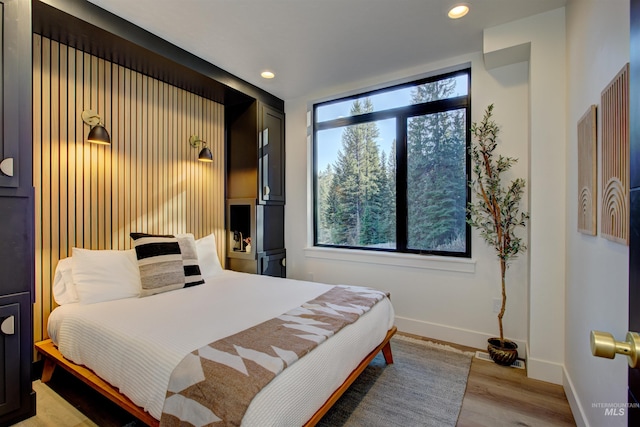 bedroom with recessed lighting, multiple windows, baseboards, and wood finished floors