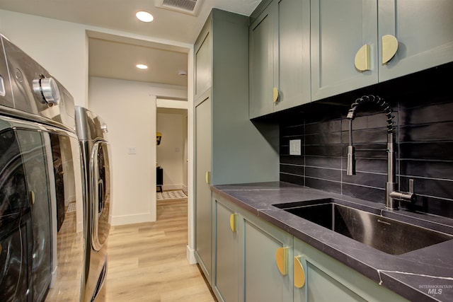 kitchen with light wood-type flooring, dark countertops, and washing machine and clothes dryer