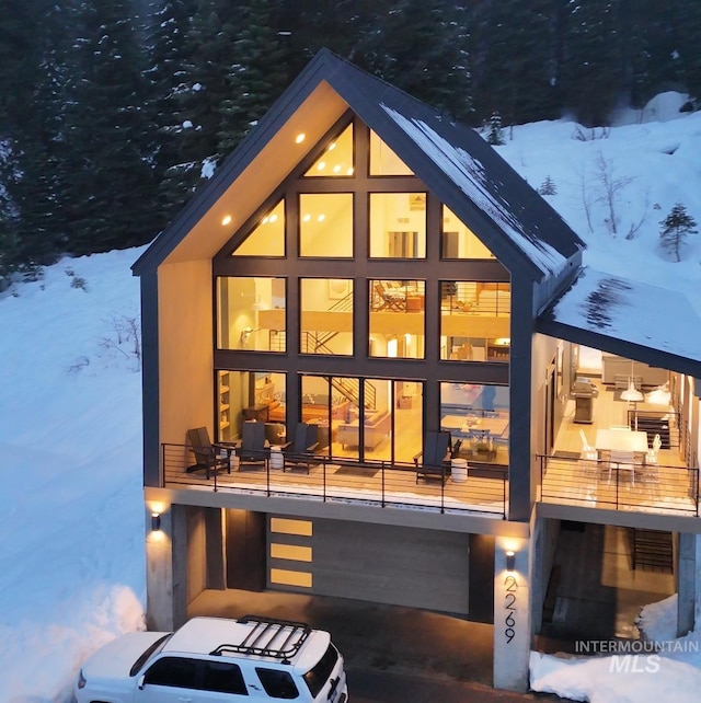 snow covered rear of property featuring a balcony