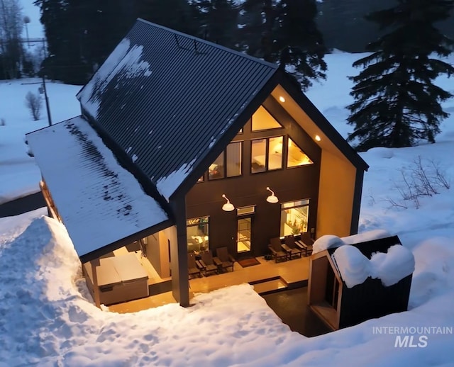 snow covered rear of property featuring a patio area