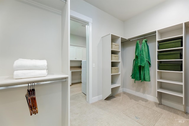 walk in closet featuring light colored carpet