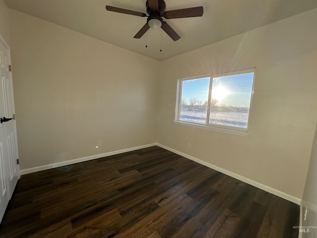 empty room with dark wood-style floors, ceiling fan, and baseboards