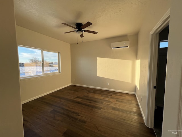 unfurnished room featuring baseboards, a ceiling fan, dark wood-style floors, a textured ceiling, and a wall mounted AC