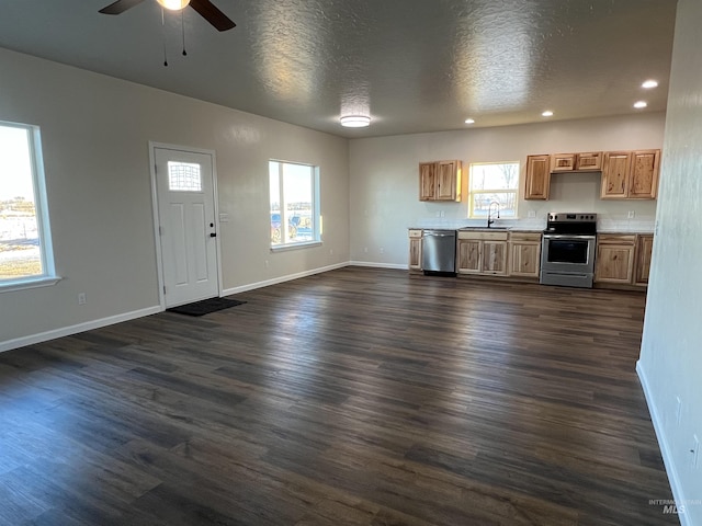 kitchen with appliances with stainless steel finishes, dark wood finished floors, open floor plan, and a sink