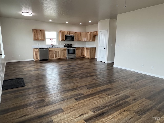 kitchen with stainless steel appliances, dark wood finished floors, a sink, and light countertops