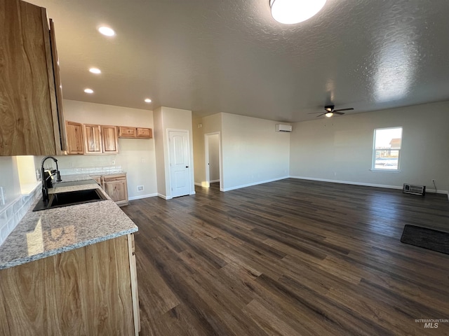 kitchen featuring a textured ceiling, baseboards, dark wood finished floors, and a sink