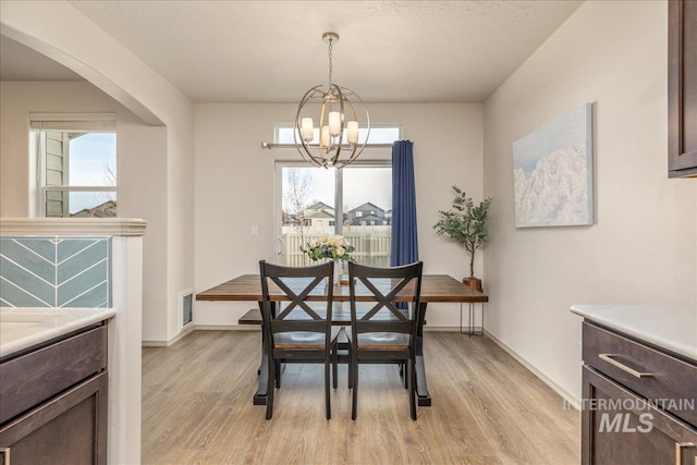 7566 W Corona Dr, Boise, ID 83709 - dining room with a chandelier, light wood finished floors, arched walkways, and baseboards