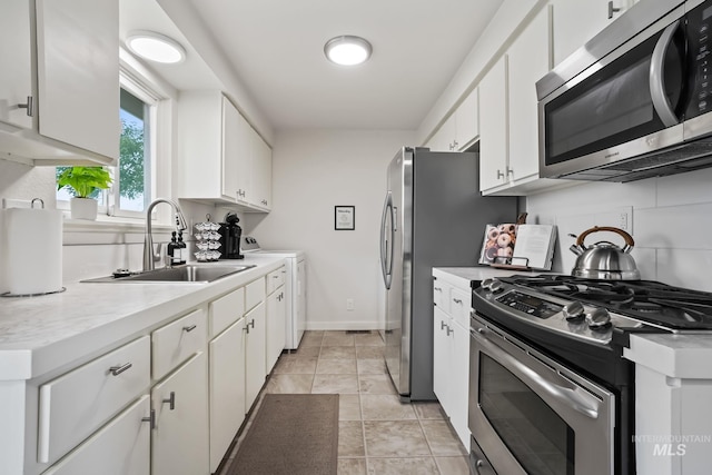 kitchen featuring white cabinets, a sink, light countertops, washer / clothes dryer, and stainless steel appliances