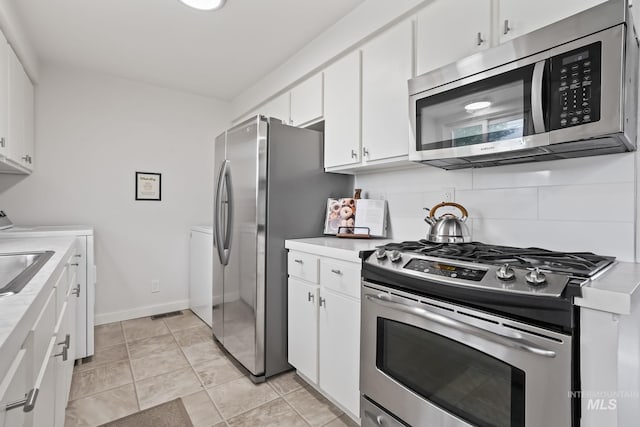 kitchen with light countertops, appliances with stainless steel finishes, baseboards, and white cabinetry