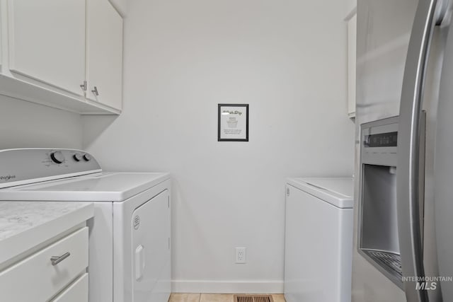 washroom with cabinet space, baseboards, and washer and clothes dryer