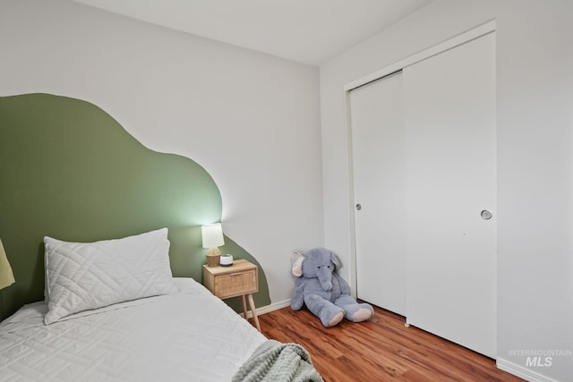 bedroom featuring baseboards, wood finished floors, and a closet