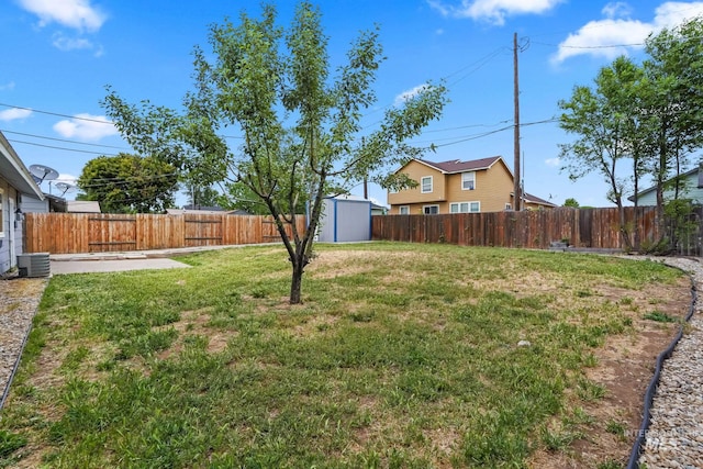 view of yard with an outdoor structure, a fenced backyard, and a shed