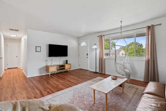 living area with baseboards, visible vents, and wood finished floors