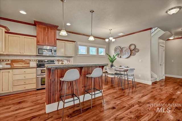 1512 N 28th St, Boise, ID 83703 - kitchen featuring appliances with stainless steel finishes, a kitchen bar, tasteful backsplash, ornamental molding, and a center island