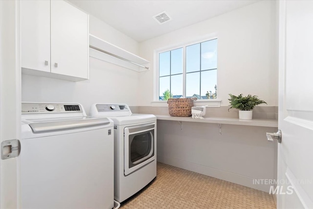 laundry area with light floors, washer and clothes dryer, cabinet space, and visible vents