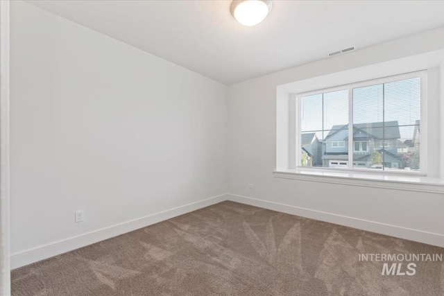 spare room featuring baseboards, carpet, lofted ceiling, and visible vents