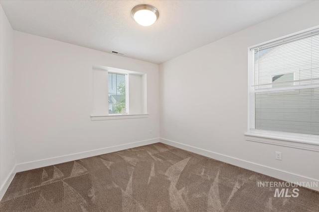 empty room featuring baseboards, carpet, and visible vents