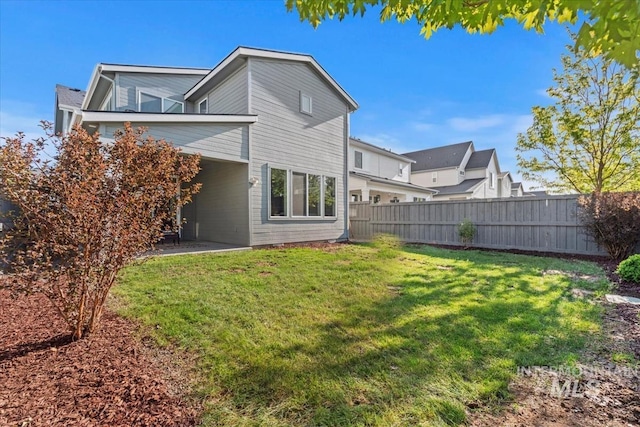 back of house with fence and a lawn