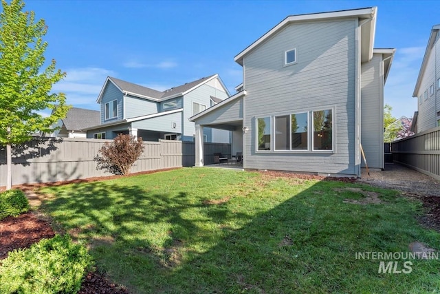 rear view of property featuring a lawn, fence, and a patio area
