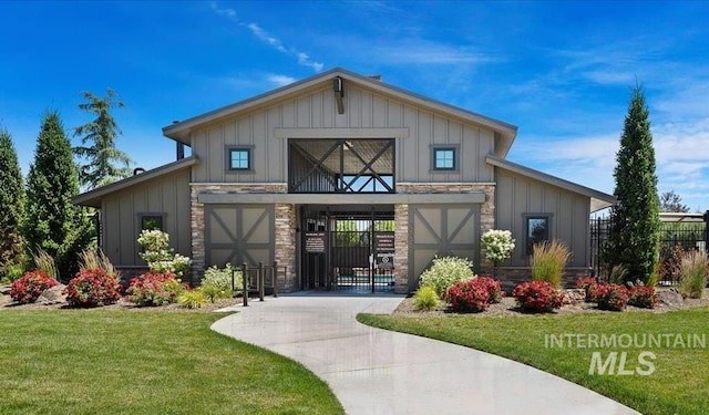 entrance to property with board and batten siding, a yard, driveway, and stone siding