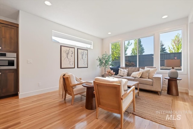 living area with baseboards, recessed lighting, and light wood-style flooring