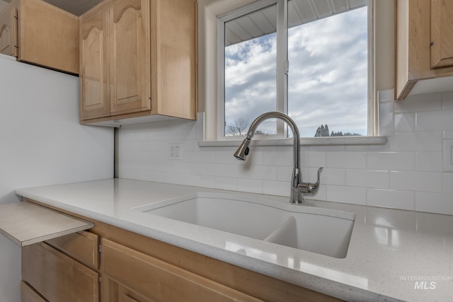 kitchen with backsplash, light stone counters, sink, and light brown cabinets