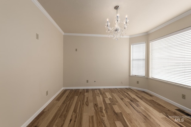 spare room featuring hardwood / wood-style flooring, ornamental molding, and an inviting chandelier