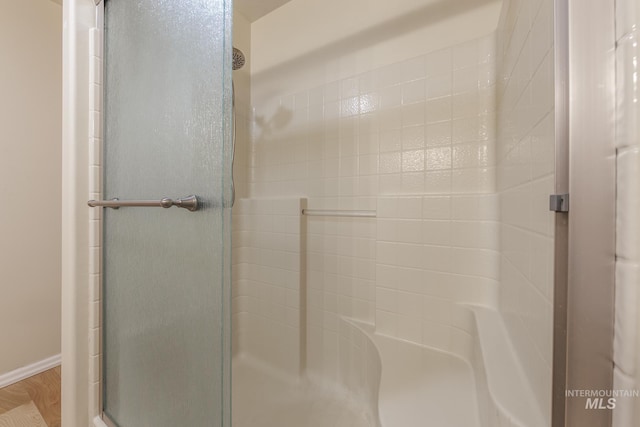 bathroom featuring hardwood / wood-style floors and a shower with shower door