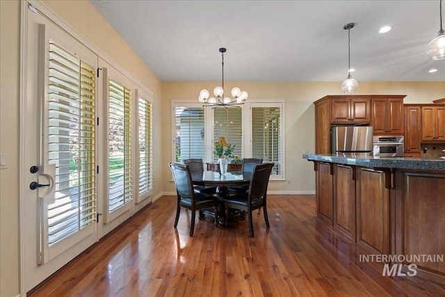 dining area featuring dark wood-type flooring and a notable chandelier