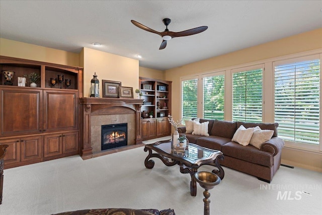 living room featuring ceiling fan, a fireplace, and light carpet