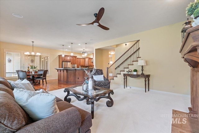 carpeted living room featuring ceiling fan with notable chandelier