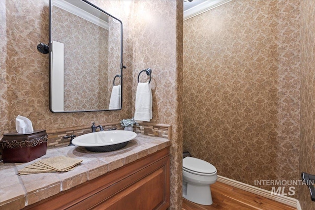 bathroom featuring vanity, toilet, crown molding, and hardwood / wood-style floors