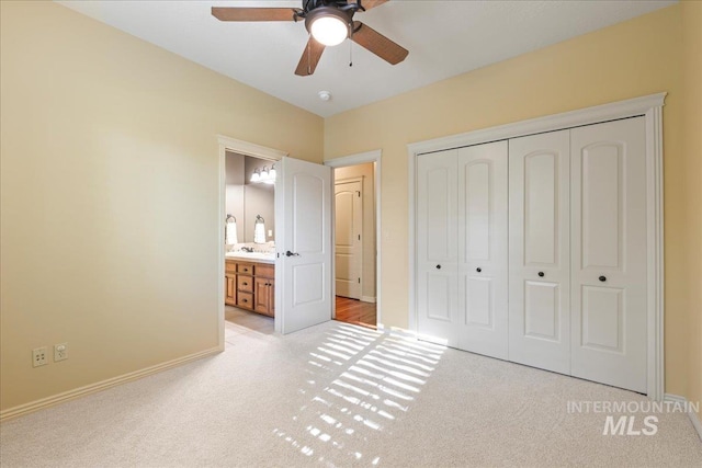 unfurnished bedroom featuring connected bathroom, ceiling fan, light colored carpet, and a closet