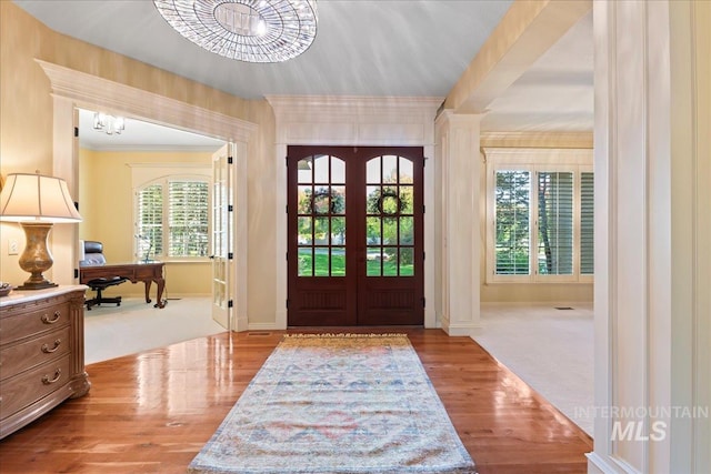 entryway with light hardwood / wood-style flooring, an inviting chandelier, and french doors