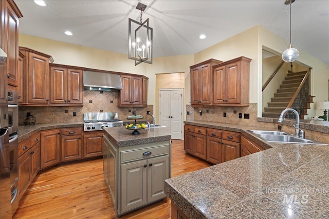 kitchen with light hardwood / wood-style floors, backsplash, a center island, decorative light fixtures, and sink