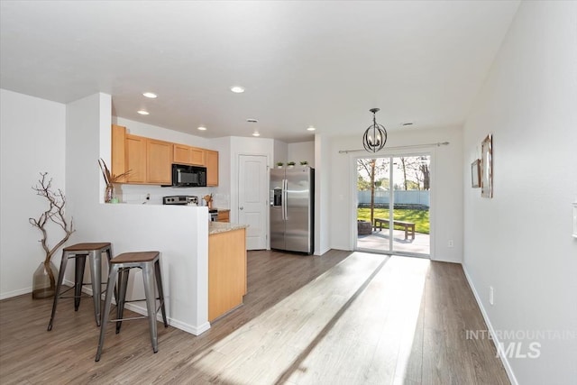 kitchen with appliances with stainless steel finishes, light wood-type flooring, light countertops, baseboards, and a peninsula