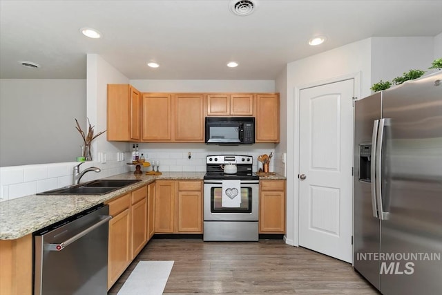 kitchen with light stone countertops, appliances with stainless steel finishes, a sink, tasteful backsplash, and visible vents