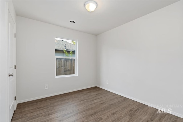 spare room with baseboards and wood finished floors