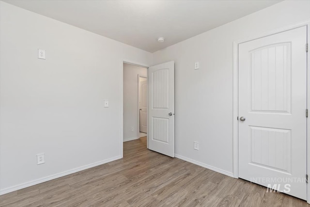 unfurnished bedroom with baseboards and light wood-type flooring