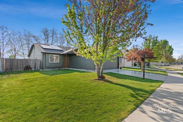 view of front of property with driveway, a front yard, a garage, fence, and roof mounted solar panels