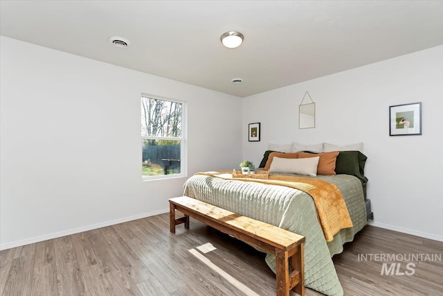bedroom featuring baseboards, wood finished floors, and visible vents