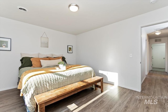 bedroom with baseboards, wood finished floors, and visible vents