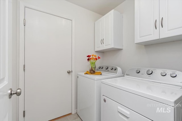 laundry area featuring light tile patterned floors, separate washer and dryer, and cabinet space