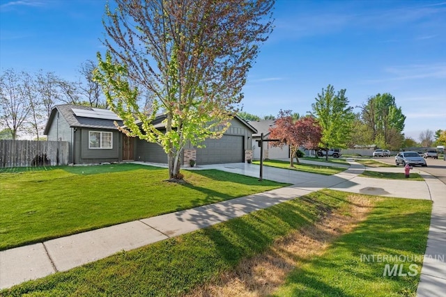 view of front of property featuring a garage, a front lawn, fence, concrete driveway, and solar panels